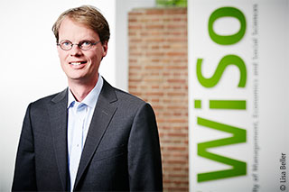 Porträt von Professor Ockenfels vor grünem WISO-Logo halbnah. 